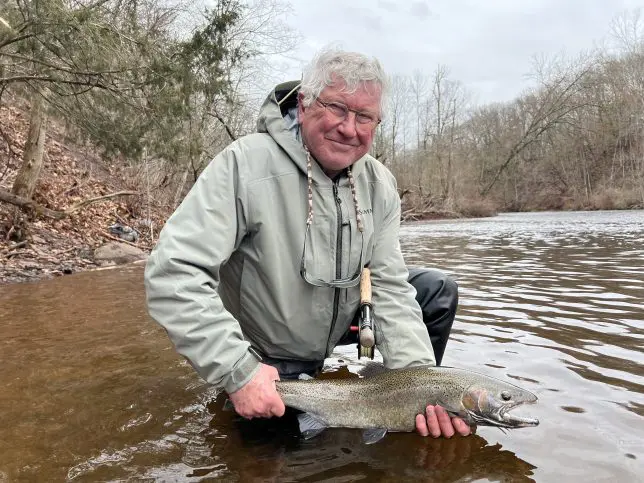 man-proudly-holding-medium-sized-fish-in-river-in-the-fall yacht-club-6